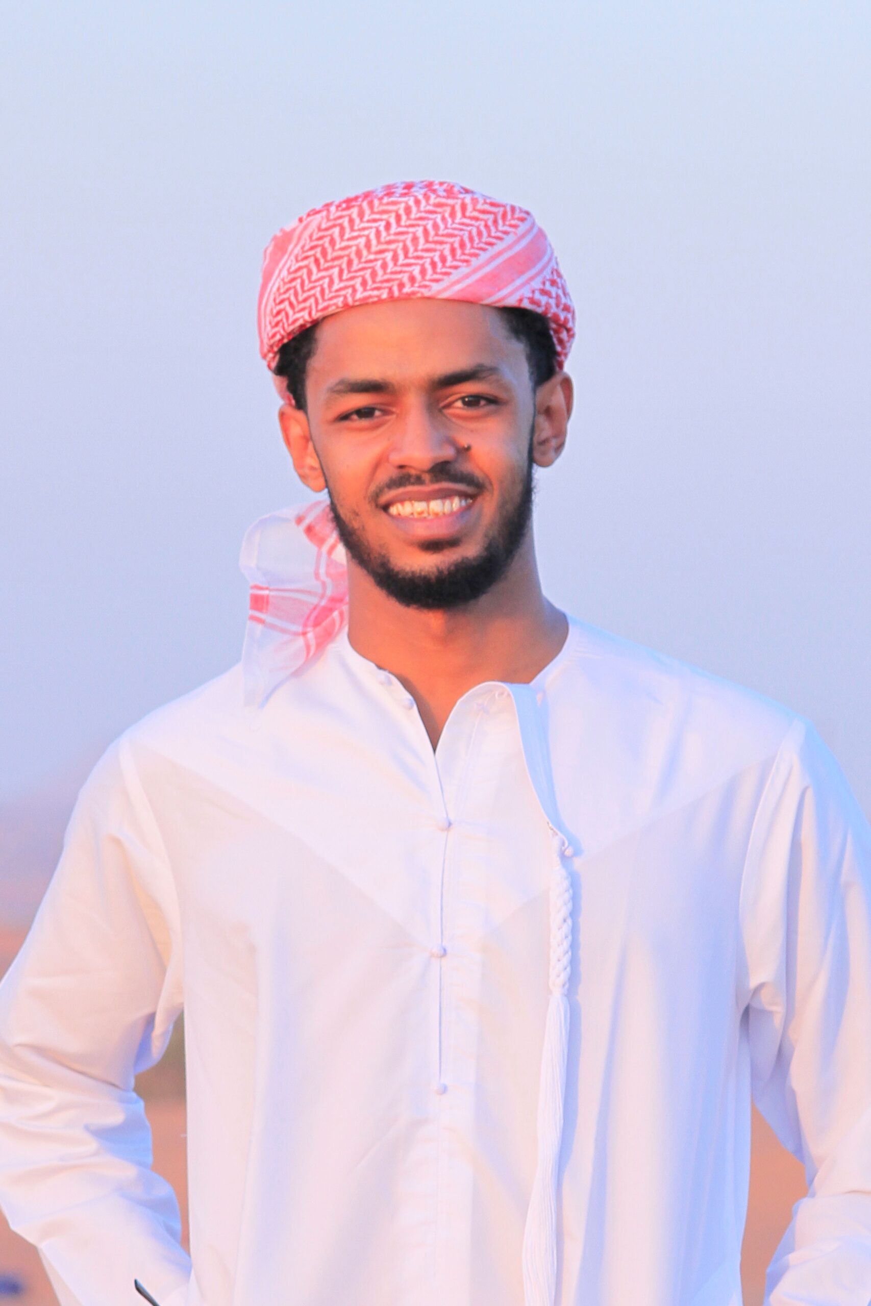 صيانة الغسالات Portrait of a smiling young Middle Eastern man wearing traditional clothing outdoors.